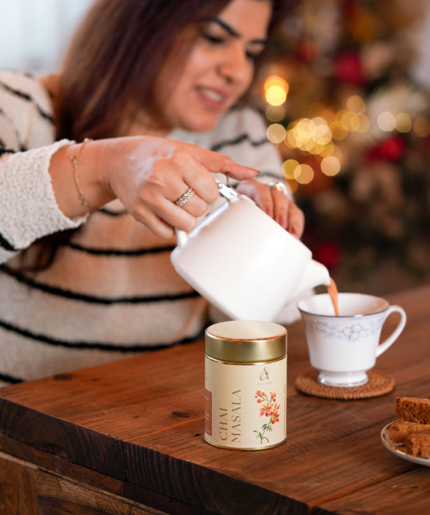 A woman gracefully pours tea into a delicate cup, creating a soothing and aromatic beverage.