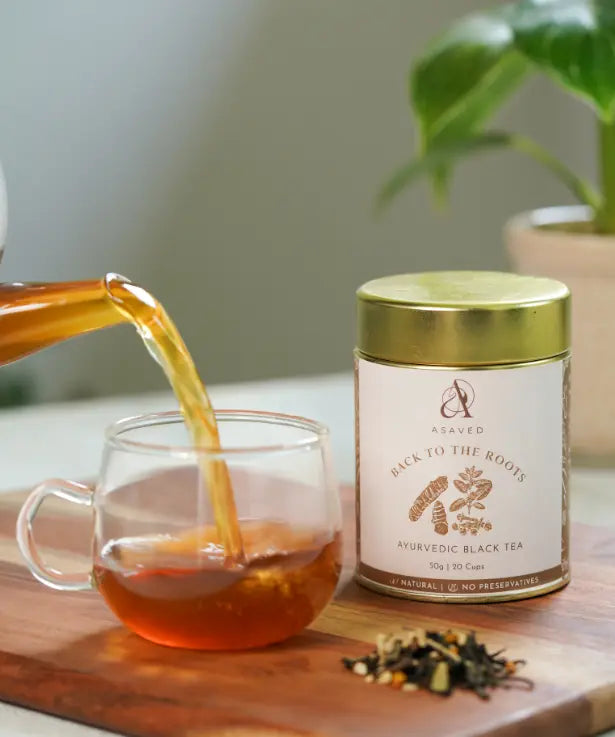 A cup of tea being poured into a cup on a wooden cutting board.
