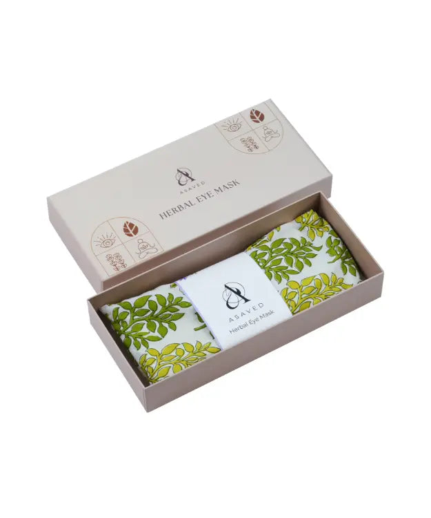 Herbal eye mask packaged in a box with a green leafy pattern visible through the open lid.