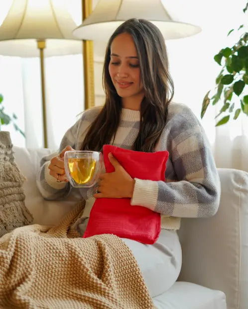 A girl holding ASAVED's Herbal Pack with red cotton cover — filled with fenugreek, lavender and rosemary for period cramp, joint pain and muscle relief