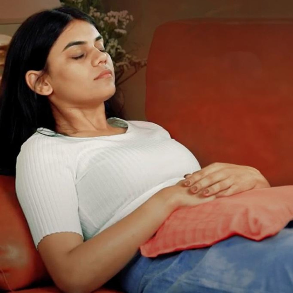 Woman using ASAVED Herbal Pack on her abdomen — microwavable herbal heat compress for period cramps, joint pain and muscle tension relief